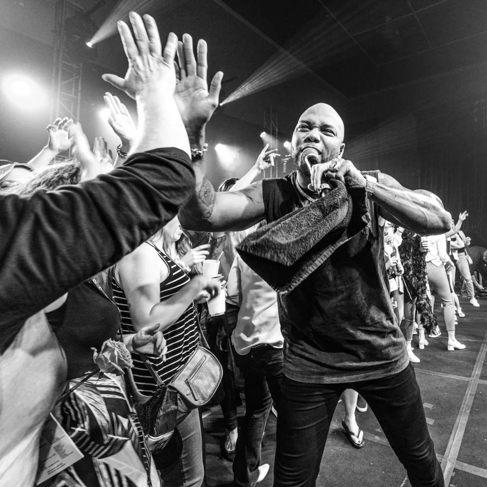 Flo Rida performing on stage with raised audience hands (black and white)