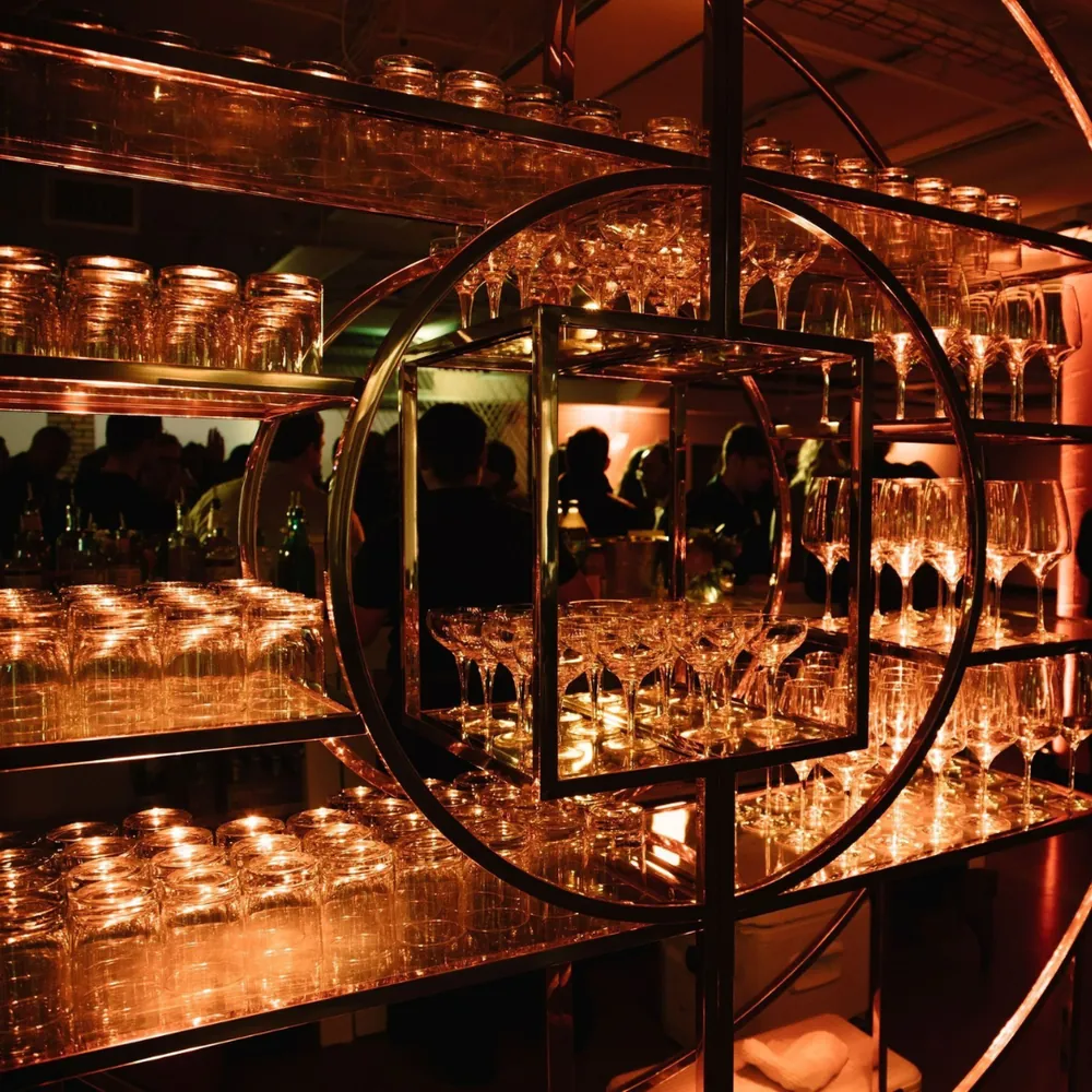 Glassware display lit in warm pink-orange tones at a wine event