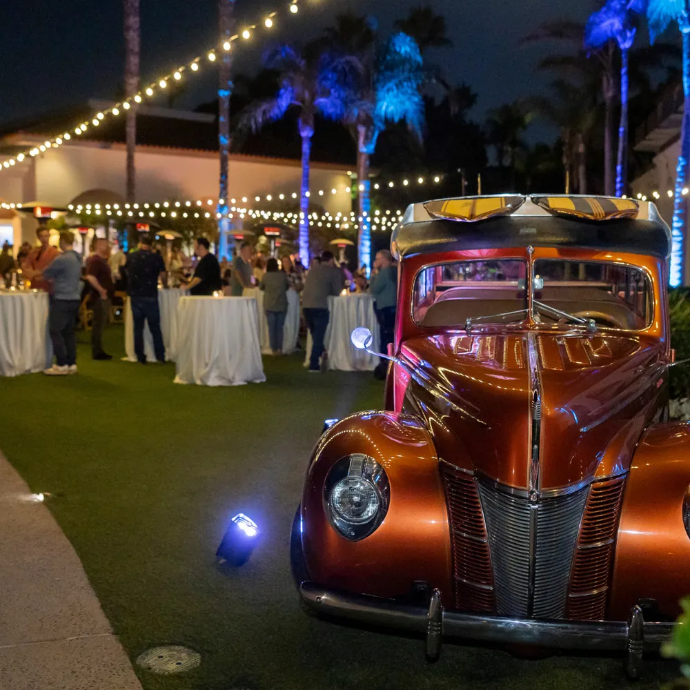 Vintage woody car at outdoor evening event with palm trees and string lights